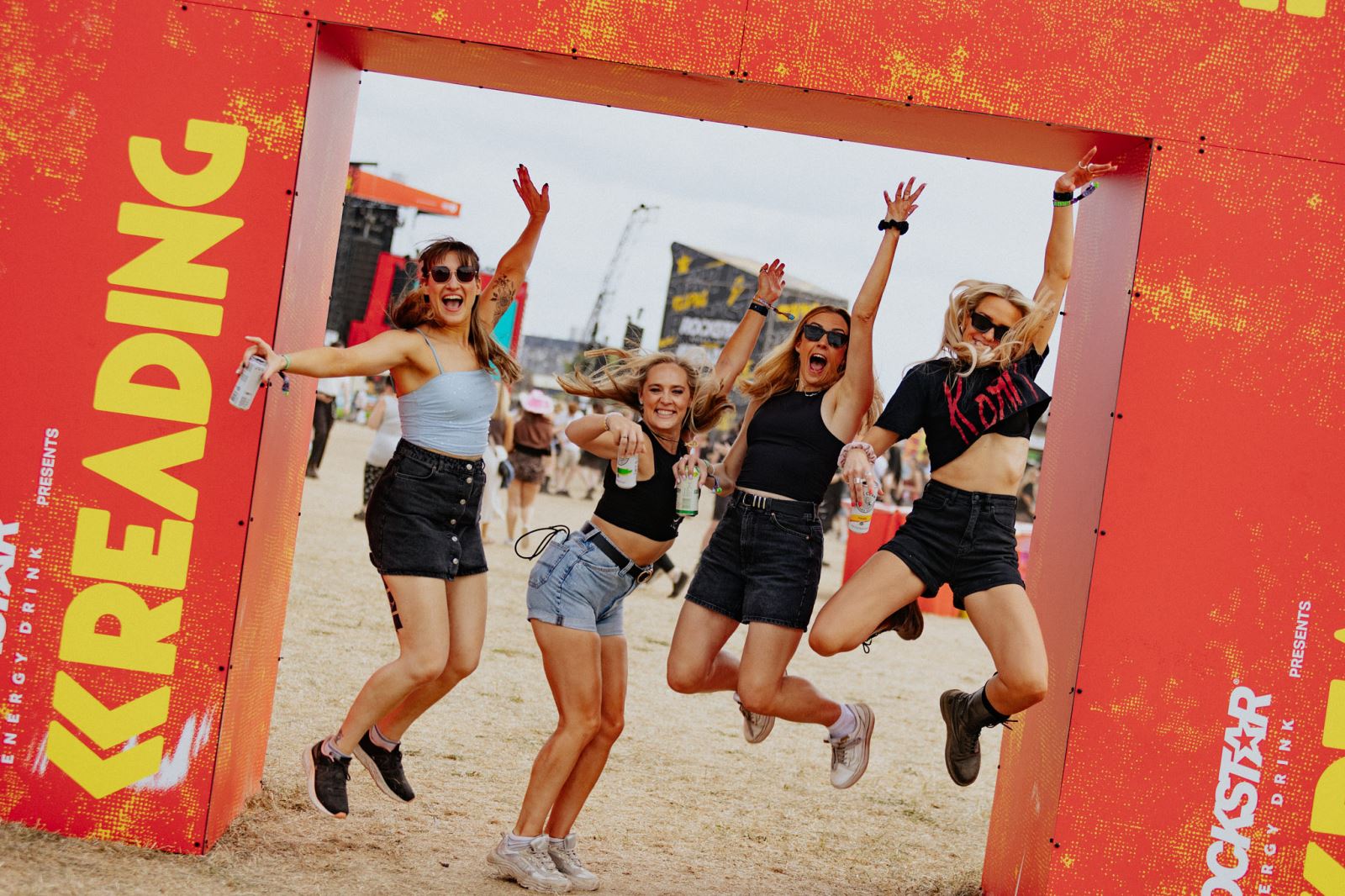 Girls jumping in Reading Festival sign
